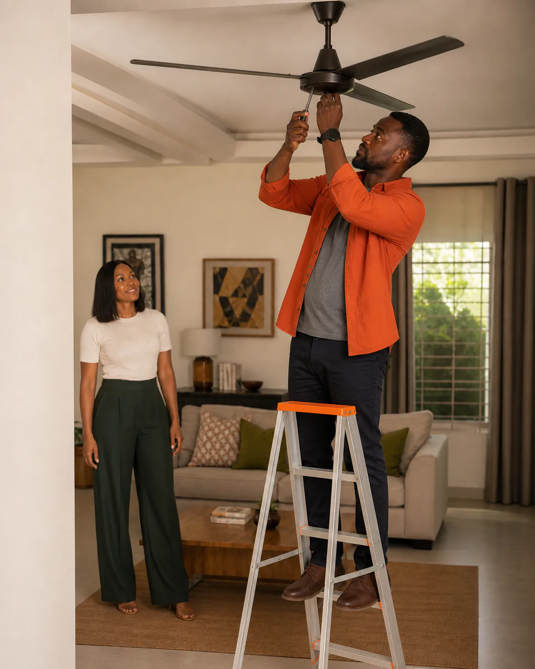A professional handyman safely repairing a ceiling fan while the requester observes